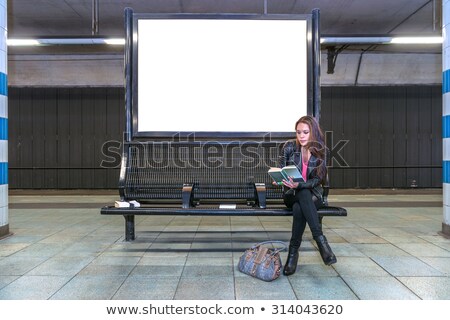 [[stock_photo]]: Railway Station Billboard And Reading Woman