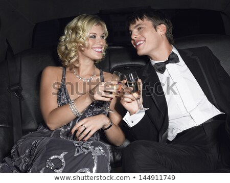 Foto d'archivio: Elegant Young Couple Toasting Champagne Flutes In Limousine