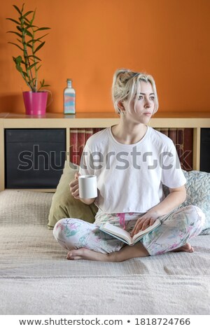 Woman Sitting Indoors On Bed Reading Book Looking Aside Stockfoto © 2Design