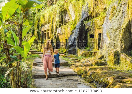 Foto stock: Mom And Son On Background Of Gunung Kawi Ancient Carved In The Stone Temple With Royal Tombs Bali