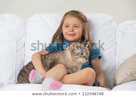 Foto d'archivio: Cute Little Girl Hugging Tabby Cat With Love Looking Away