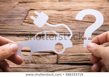 Stockfoto: Holding Paper Electric Car And Question Mark At Table