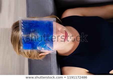 Foto d'archivio: Woman Applying Ice Gel Pack On Forehead