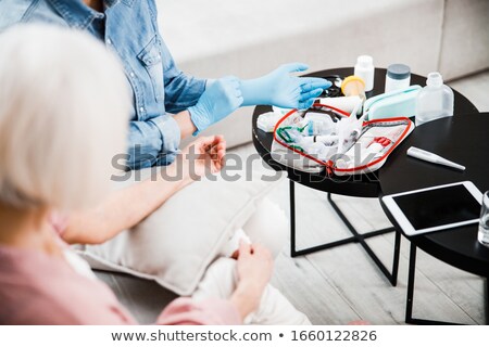 [[stock_photo]]: Mature Family Doctor Putting On Gloves