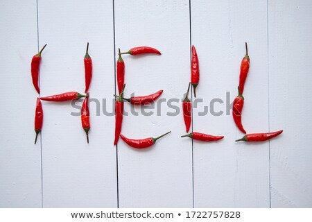 Foto d'archivio: A Word Hell Formed With Small Red Chilli Peppers Placed On White Wooden Table