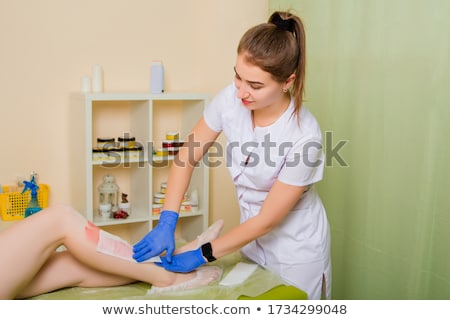 Foto d'archivio: Hair Removal Using Wax Strips At The Legs In Beauty Parlor