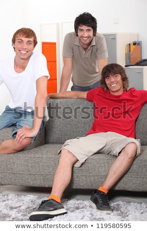 Foto stock: Housemates Relaxing Together In Their Sitting Room