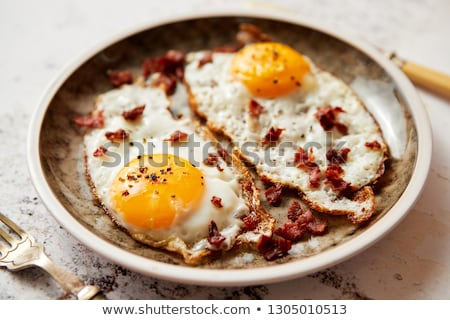 Сток-фото: Two Fresh Fried Eggs With Crunchy Crisp Bacon Served On Rustic Plate