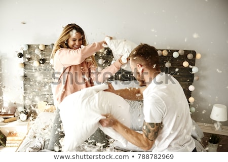 Stock fotó: Happy Couple Having Pillow Fight In Bed At Home