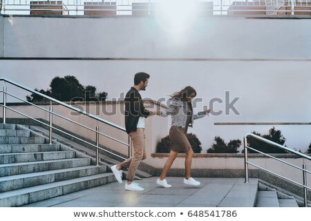 Stok fotoğraf: Image Of Beautiful Young Couple Smiling And Holding Hands Together While Walking Down City Stairs