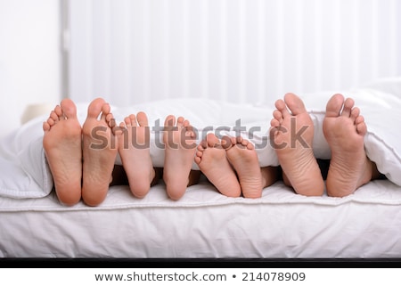 Stok fotoğraf: Pairs Of Feet In A Bed