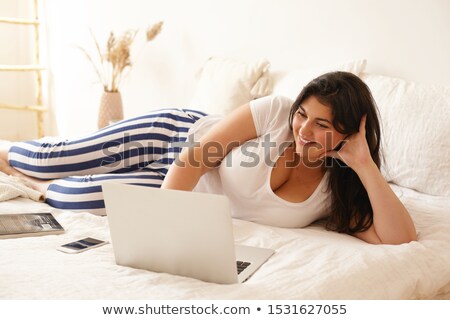 Foto stock: A Woman Lying On The Bed Using A Laptop And Looking At The Screen