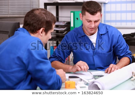 Foto stock: Skilled Tradesmen Examining A Blueprint