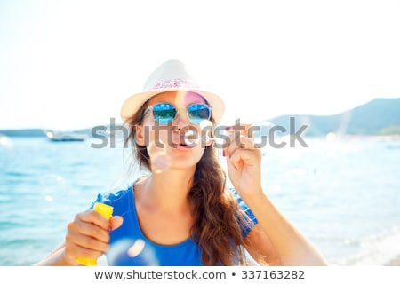 Foto d'archivio: Happy Young Girl Blowing Soap Bubbles On The Seashore