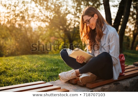 Foto stock: Cute Woman Sitting On A Bench In Park Reading Book