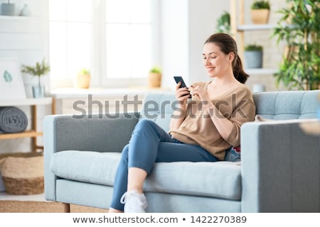 Stock photo: Young Smiling Woman Using Mobile Phone At Home