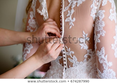 Foto d'archivio: Bridesmaids Help To Wear A Wedding Lace Dress