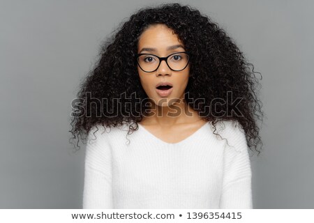 Foto stock: Candid Shot Of Shocked Beautiful Woman In Glasses With Dark Frizzy Hair Keeps Jaw Dropped From Amaz