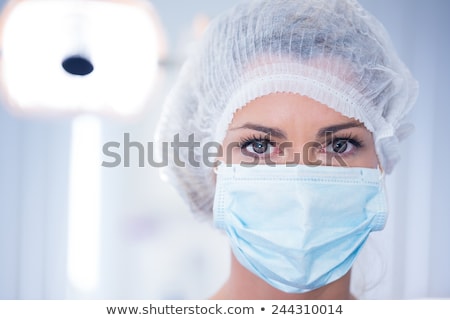 Stock fotó: Dentist In Surgical Mask And Cap Looking At Camera