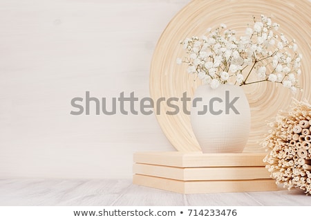 Foto d'archivio: Soft Home Decor Of Beige Bamboo Dish And White Small Flowers In Ceramic Vase On White Wood Backgrou