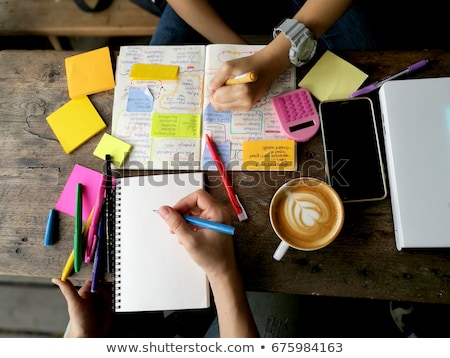 Stock foto: Teenage Man Sitting By Wooden Table Reading And Writting On Note