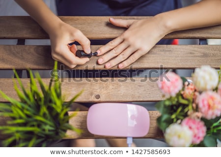 Stockfoto: Young Woman Makes Manicure With Gel Polish And Uv Lamp In Pink Shades