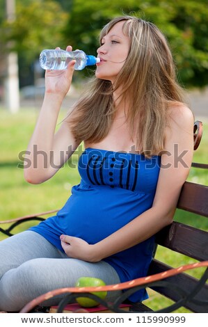 Stok fotoğraf: Pregnat Woman With Bottle Of Water Sitting On Bench