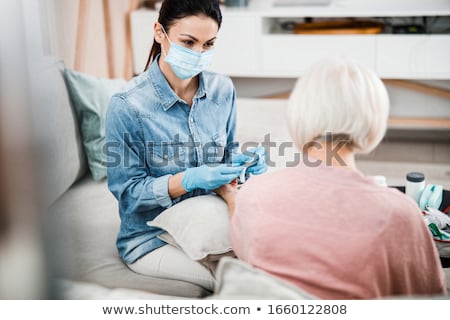 Stok fotoğraf: A Woman With A Face Mask Holding A Vaccine