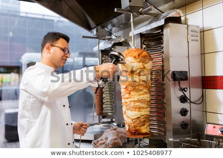 Foto stock: Chef Slicing Doner Meat From Spit At Kebab Shop