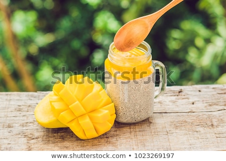 Stok fotoğraf: Chia Seed Pudding With Almond Milk And Fresh Mango Topping With Levitating Spoon