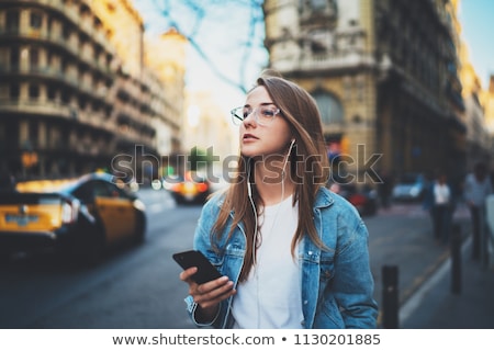 ストックフォト: Cheerful Blond Girl Listening To Music On Her Smartphone