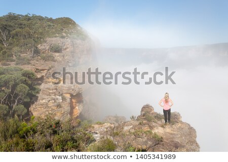 Stockfoto: Female Hiker Standing On A Rock Pinnacle With Rising Fog From Valley