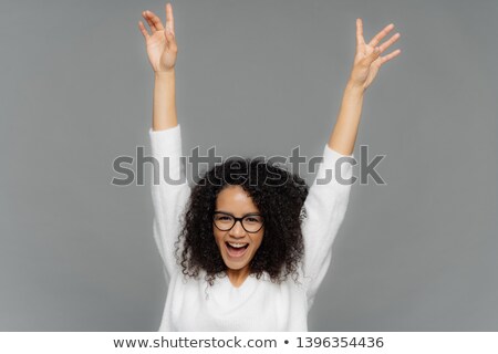 Stock photo: Happy Pleased Young Woman Raises Hands Up Being In High Spirit Dances Over Grey Background Celebr