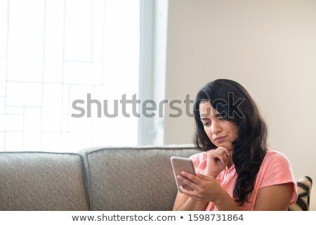 [[stock_photo]]: Concerned Woman In Sofa Looking At Phone