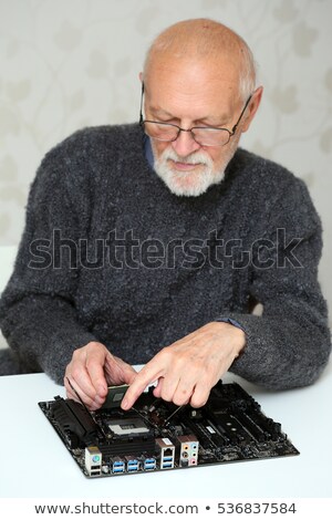 Foto stock: Elderly Man Installs Cpu To Motherboard