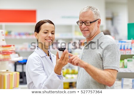 Foto d'archivio: Apothecary Showing Drug To Senior Man At Pharmacy