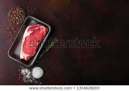 Stock fotó: Raw Sirloin Beef Steak In Plastic Tray With Knife And Fork On Rusty Background Salt And Pepper With