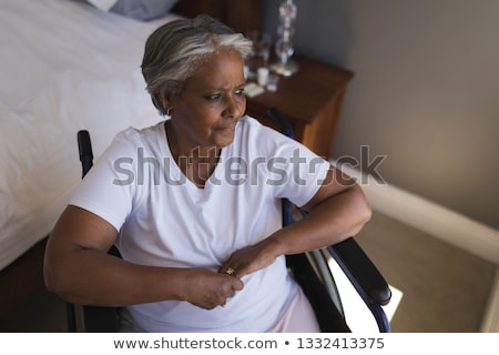 Stockfoto: Upper Section Of A Thoughtful Disabled Senior African American Woman Looking Worried Through Window