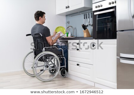 Stock foto: Handicapped Man Cleaning Dishes In Kitchen