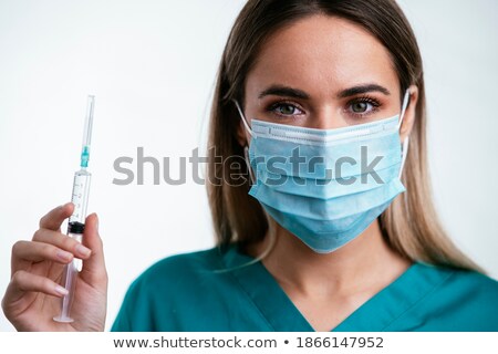 Stock photo: Portrait Of Woman Doctor In Mask Standing And Holding Syringe
