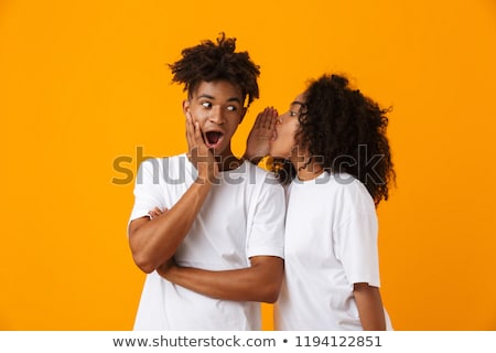[[stock_photo]]: Emotional Young Cute African Couple Posing Isolated Over Yellow Background Gossiping Tell Secret