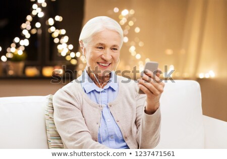 Stok fotoğraf: Senior Woman With Smartphone And Earphones On Xmas