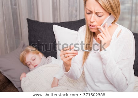 Foto stock: Worried Mother With Thermometer And Smartphone Calling Doctor Home