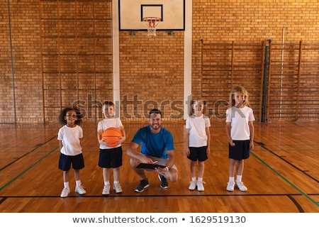 Foto stock: Front View Of Happy Basketball Coach And Schoolkids Looking At Camera At Basketball Court