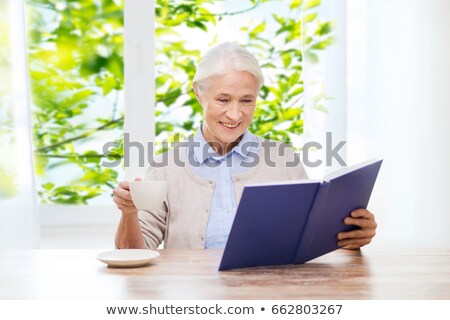 Stok fotoğraf: Smiling Woman Sittin At The Table With Beverage Over Gray Background