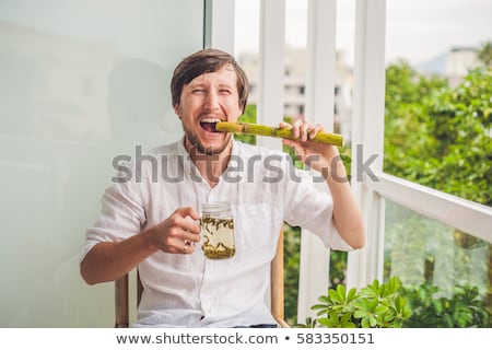 Stock fotó: Cane Sugar Concept The Man Jokingly Eating Sugar Cane And Drinks Tea