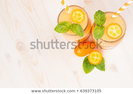 Stockfoto: Freshly Blended Orange Citrus Smoothie In Glass Jars With Straw Mint Leaf Copy Space White Wooden