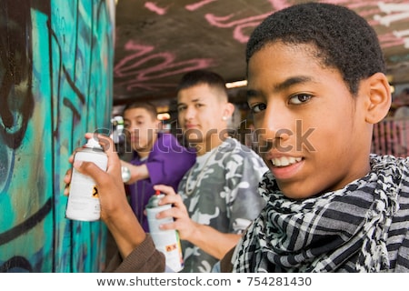 Stok fotoğraf: Teenage Gang Doing Graffiti On A Wall