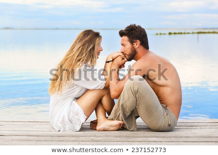 Imagine de stoc: Couple Kissing At Sunset Sitting In Jetty