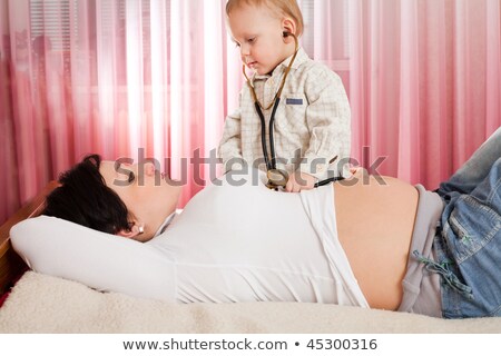 Foto stock: Childrens Hand With Stethoscope On Pregnant Belly